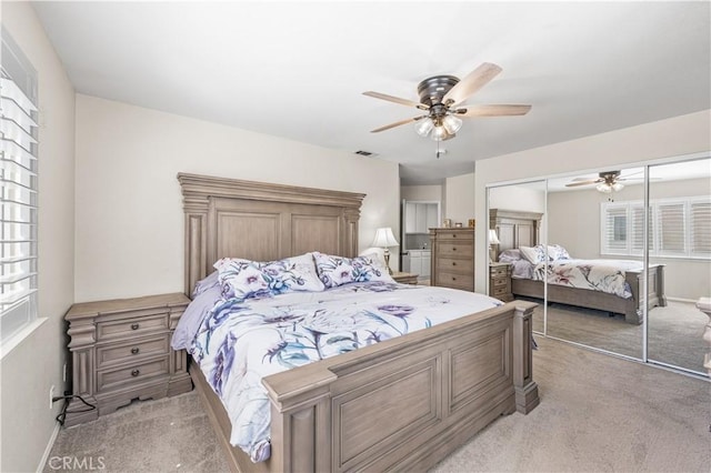 bedroom with a closet, baseboards, light colored carpet, visible vents, and ceiling fan
