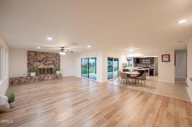 living room with a fireplace, light wood-style flooring, baseboards, ceiling fan, and recessed lighting