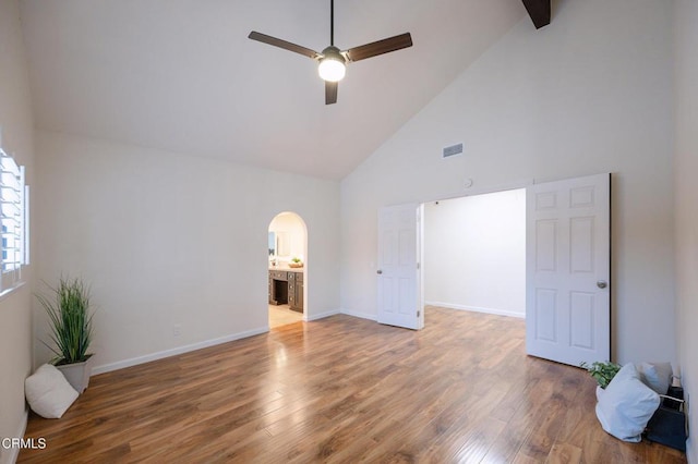 unfurnished bedroom featuring baseboards, visible vents, wood finished floors, and arched walkways