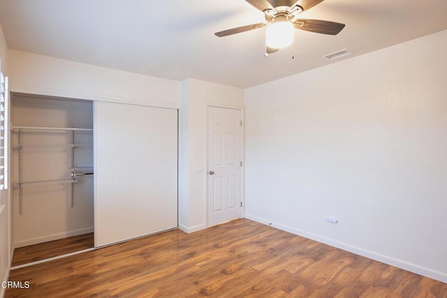 unfurnished bedroom with baseboards, visible vents, a ceiling fan, a closet, and wood finished floors