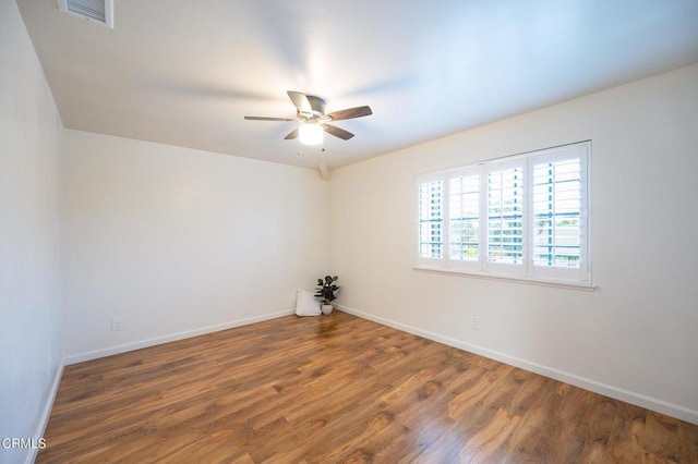 empty room with baseboards, visible vents, wood finished floors, and ceiling fan