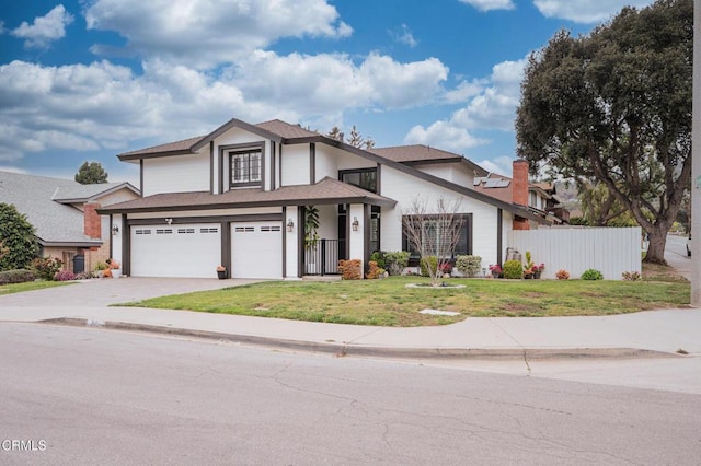 traditional home featuring fence, an attached garage, a front yard, roof with shingles, and driveway