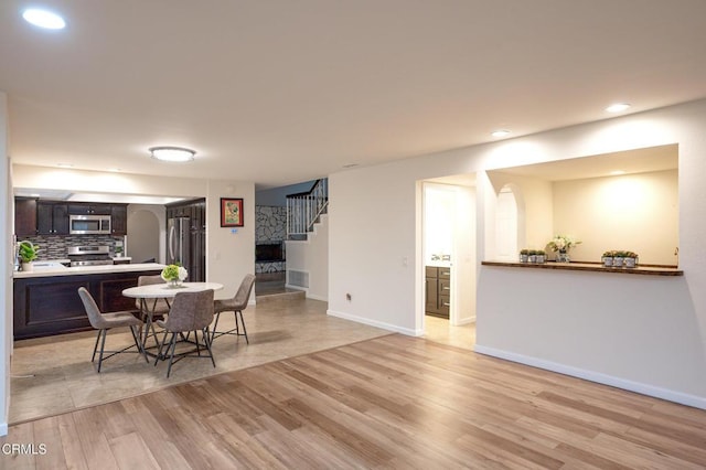 dining space with baseboards, recessed lighting, stairway, and light wood-type flooring