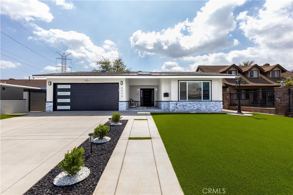 8536 Beverly Park Pl, Pico Rivera, CA 90660 - view of front of property featuring concrete driveway, fence, stone siding, a front yard, and a garage
