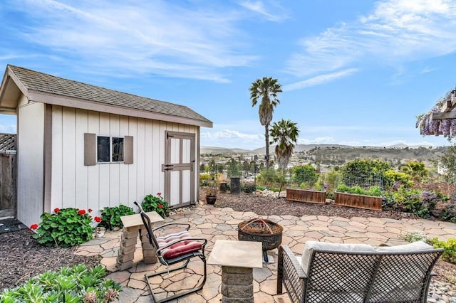 view of patio / terrace with a fire pit, an outdoor structure, and a mountain view