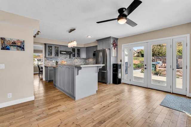 kitchen with a kitchen bar, french doors, gray cabinetry, and freestanding refrigerator