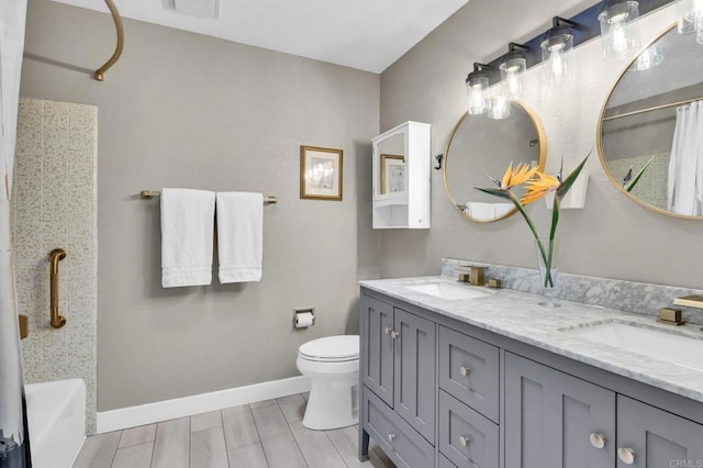 bathroom featuring baseboards, a sink, double vanity, and toilet