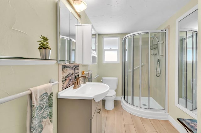 bathroom with a stall shower, baseboards, vanity, and toilet