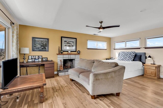 bedroom with light wood-type flooring, baseboards, a fireplace, and multiple windows