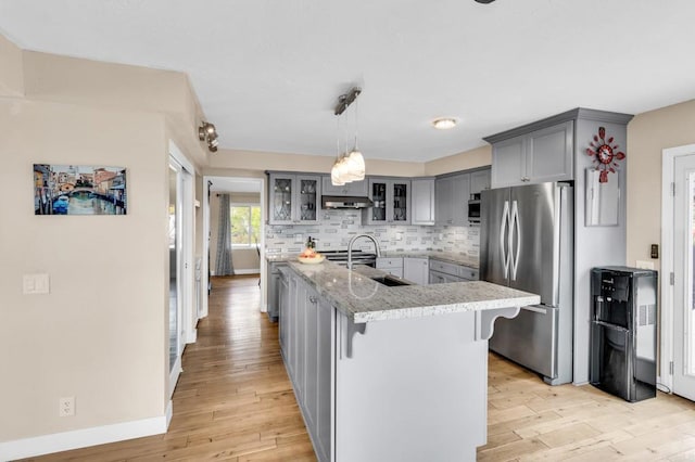 kitchen with gray cabinetry, a sink, light wood finished floors, and freestanding refrigerator