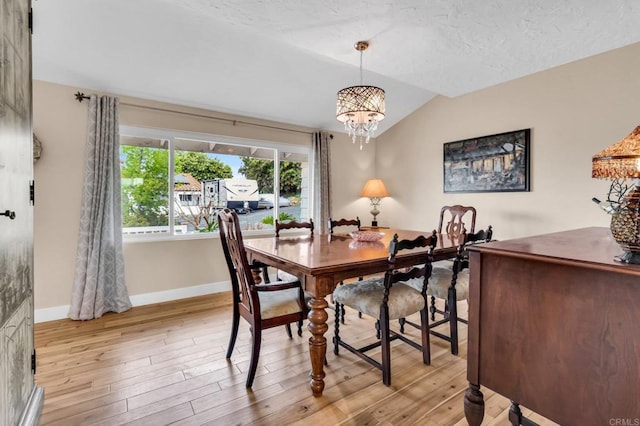 dining room featuring vaulted ceiling, light wood-style flooring, an inviting chandelier, and baseboards