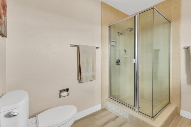 full bath featuring baseboards, a shower stall, and toilet