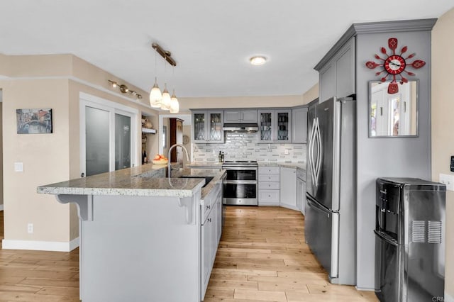 kitchen with a sink, gray cabinetry, stainless steel appliances, and light wood-type flooring