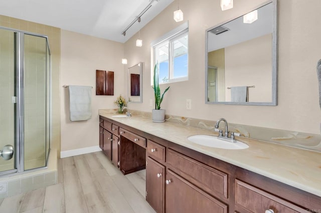 full bathroom with wood finished floors, a sink, double vanity, and a stall shower