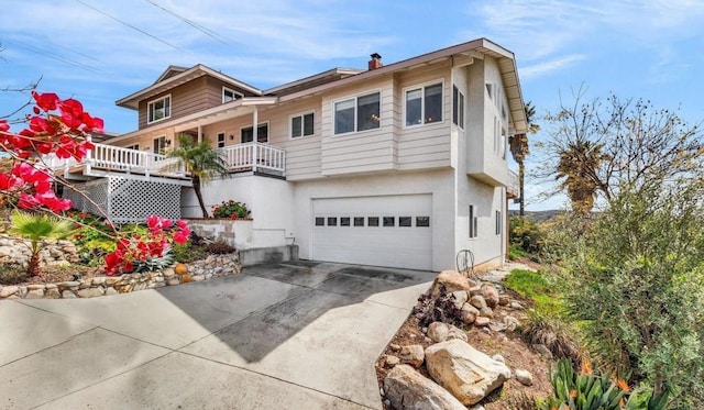 view of front of property featuring concrete driveway, a chimney, stucco siding, and a garage