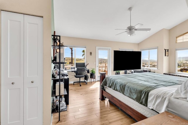 bedroom featuring access to outside, vaulted ceiling, light wood finished floors, and multiple windows