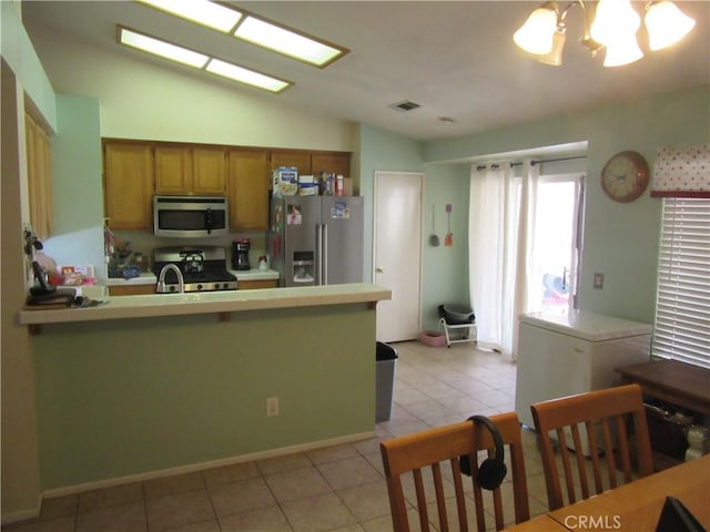 kitchen with vaulted ceiling, appliances with stainless steel finishes, tile countertops, visible vents, and an inviting chandelier
