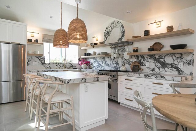164 Chestnut Ave, Carlsbad, CA 92008 - kitchen featuring open shelves, stainless steel appliances, decorative backsplash, a center island, and tile patterned flooring
