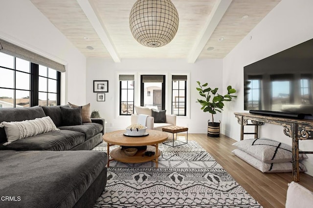 living area with plenty of natural light, lofted ceiling with beams, and wood finished floors