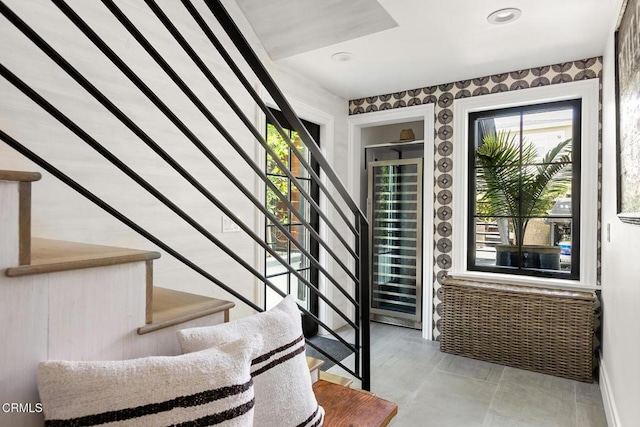 stairs featuring a wealth of natural light, wallpapered walls, and beverage cooler