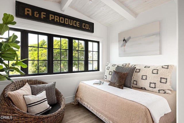 bedroom featuring lofted ceiling with beams, baseboards, and wood finished floors