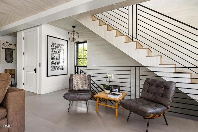 living area featuring baseboards, a notable chandelier, and finished concrete floors