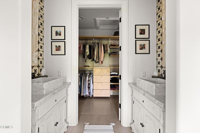 walk in closet with dark tile patterned flooring, a sink, and attic access