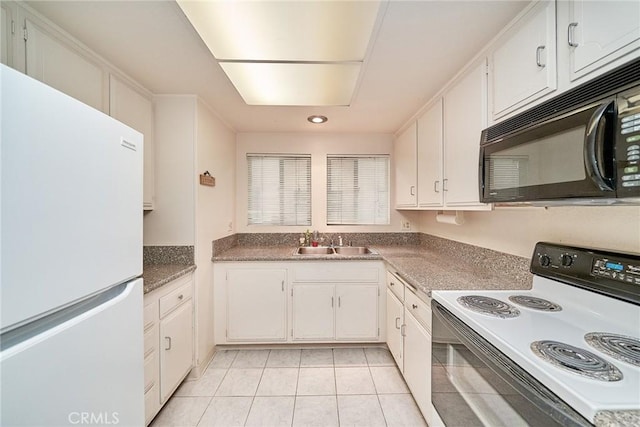 kitchen featuring electric stove, a sink, freestanding refrigerator, white cabinets, and black microwave