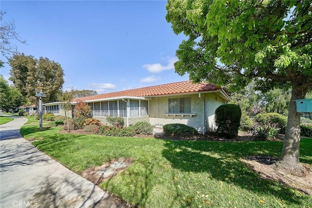 view of front of home featuring a front yard, stucco siding, and a tiled roof