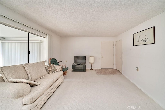 carpeted living area featuring baseboards and a textured ceiling