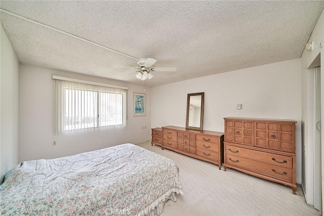 bedroom featuring light carpet, a textured ceiling, and ceiling fan