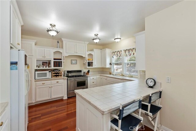 27601 Cedarwood Dr, Lake Arrowhead, CA 92352 - kitchen featuring dark wood-style flooring, white appliances, a peninsula, open shelves, and tile counters