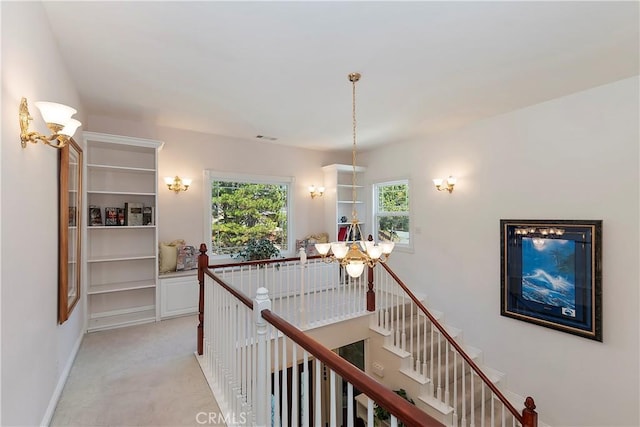 27601 Cedarwood Dr, Lake Arrowhead, CA 92352 - hall featuring light colored carpet, baseboards, an upstairs landing, visible vents, and a notable chandelier
