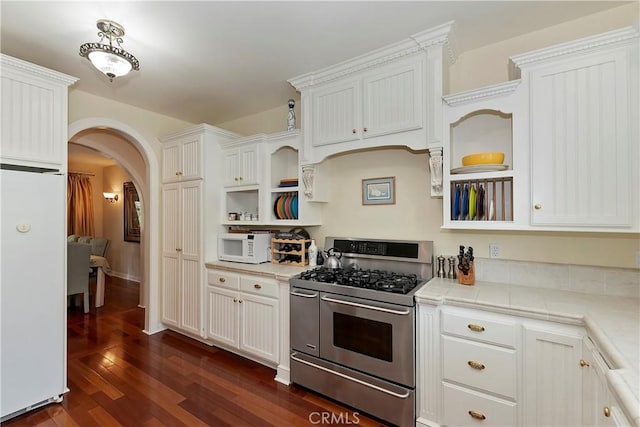 27601 Cedarwood Dr, Lake Arrowhead, CA 92352 - kitchen with range with two ovens, refrigerator, open shelves, arched walkways, and dark wood-style floors