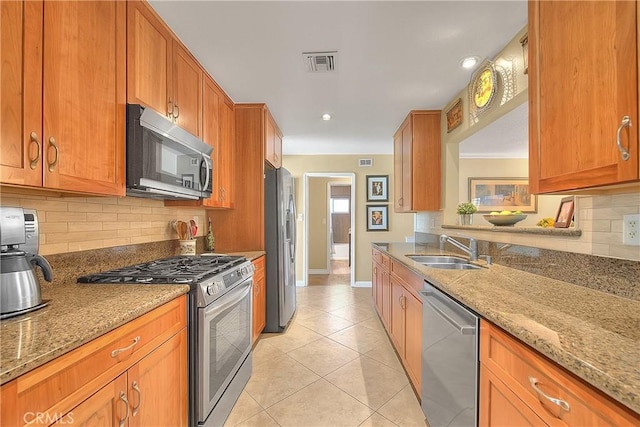 kitchen with light tile patterned flooring, a sink, light stone countertops, appliances with stainless steel finishes, and visible vents