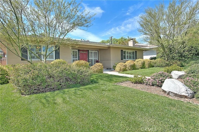 ranch-style house with a front lawn, a chimney, and stucco siding