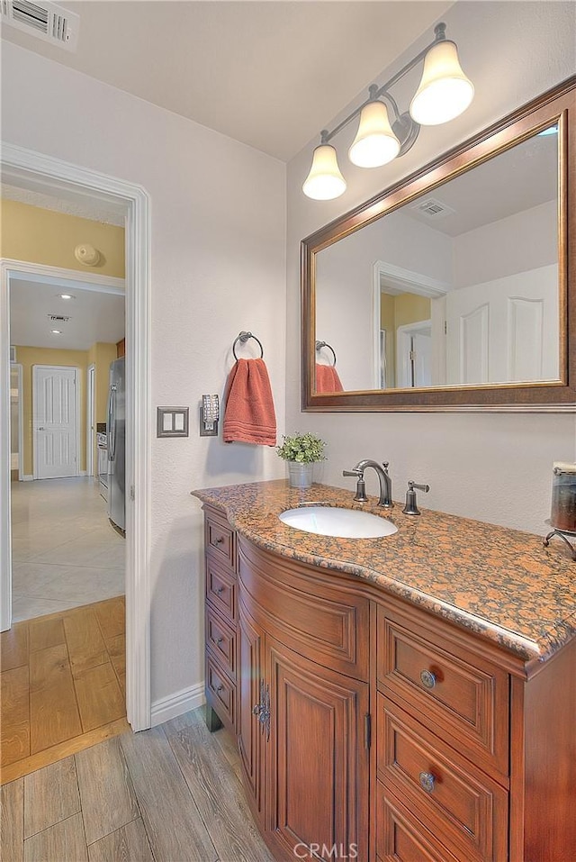 bathroom featuring wood tiled floor, visible vents, baseboards, and vanity