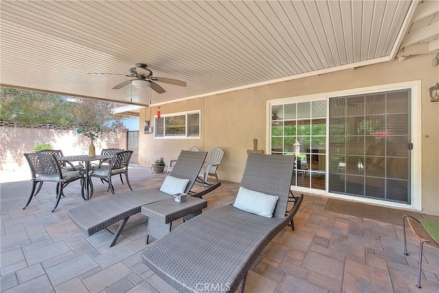view of patio / terrace with a wall mounted AC, outdoor dining area, fence, and a ceiling fan