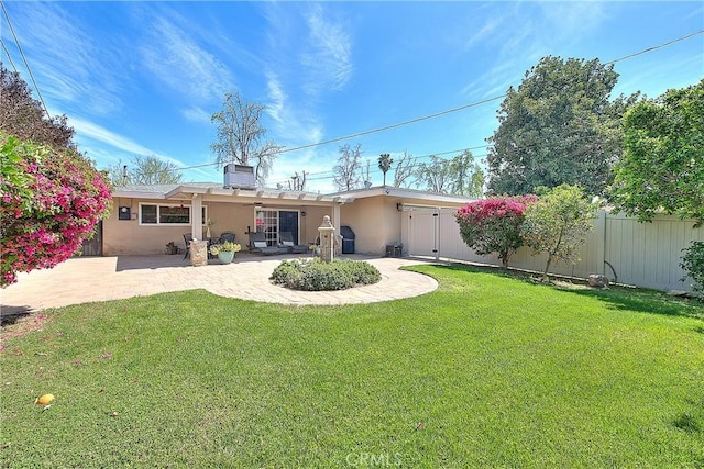 back of property with a lawn, stucco siding, fence, and a patio area