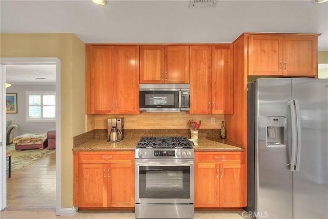 kitchen featuring backsplash, light stone countertops, and appliances with stainless steel finishes