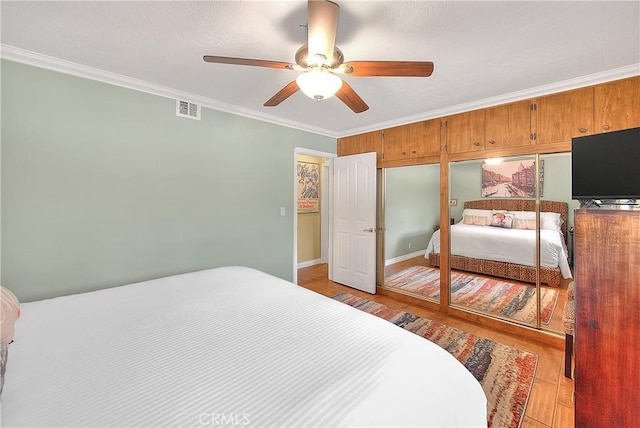 bedroom featuring ornamental molding, visible vents, ceiling fan, and light wood-type flooring