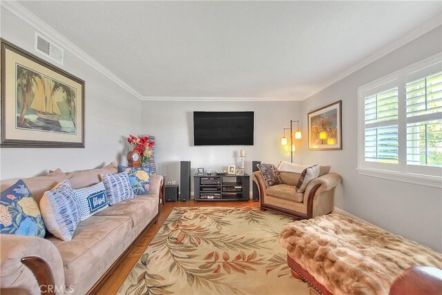 living area with visible vents, crown molding, and wood finished floors
