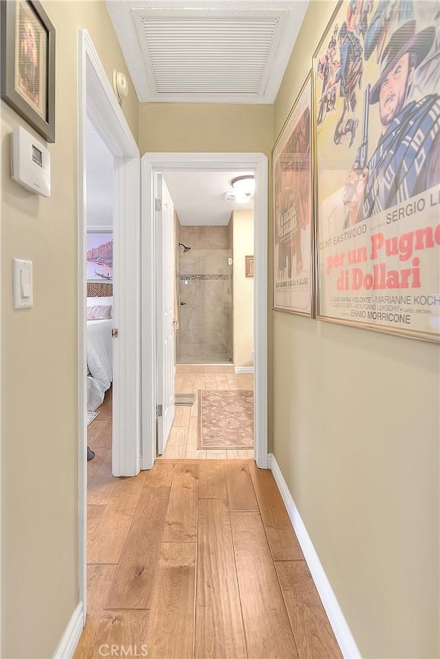 hallway featuring light wood-style flooring, baseboards, and visible vents