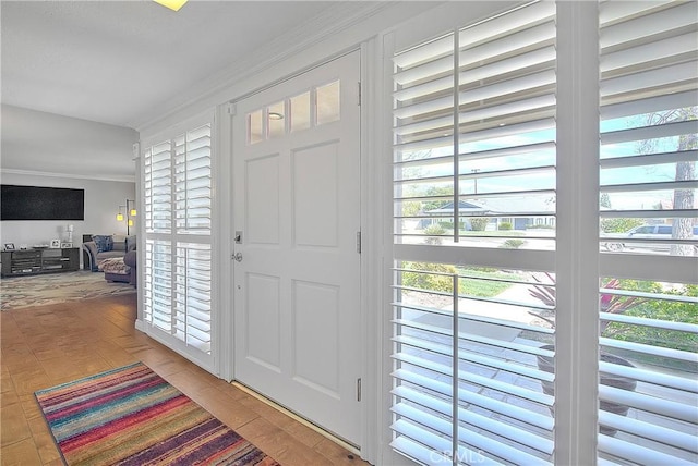 foyer entrance with ornamental molding and light wood-type flooring