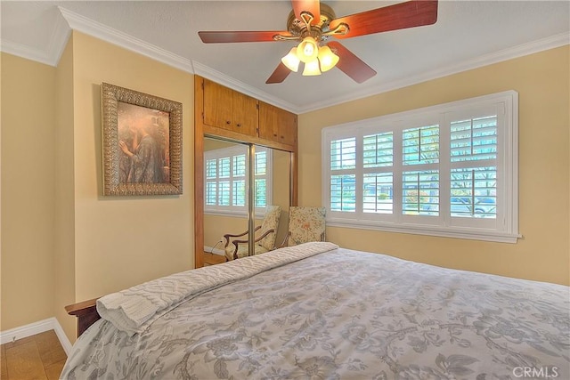 bedroom with a closet, ornamental molding, baseboards, and ceiling fan