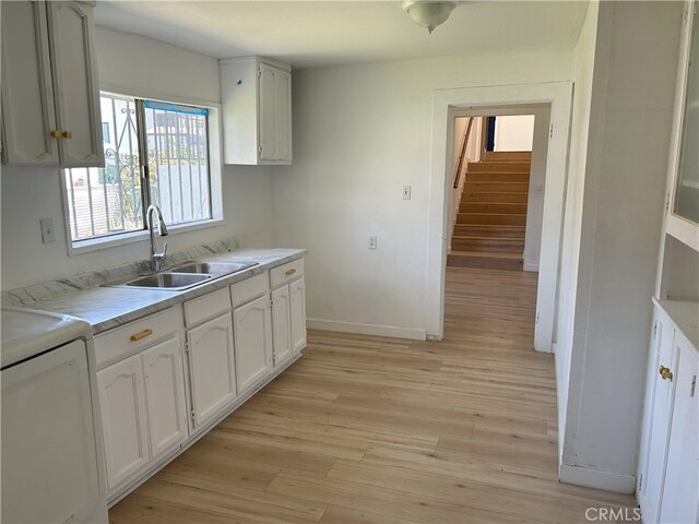 3391 Scarboro St, Los Angeles, CA 90065 - kitchen featuring a sink, washer / dryer, light wood-style floors, light countertops, and white cabinetry