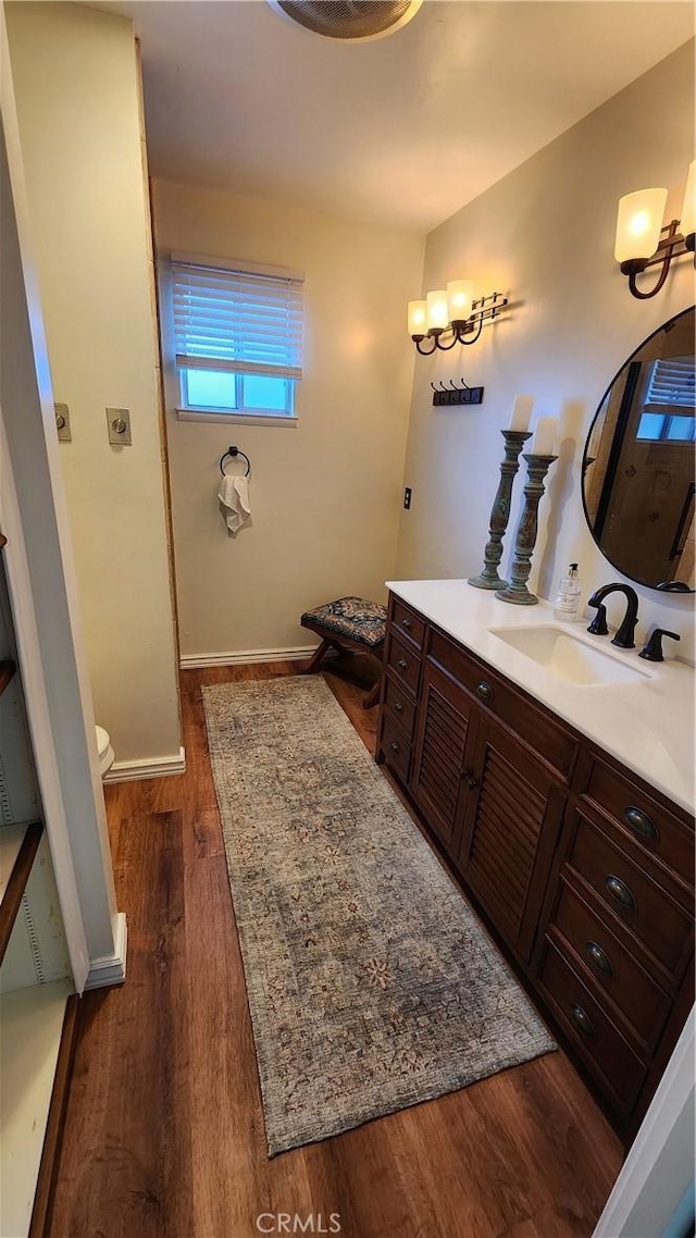 bathroom with baseboards, wood finished floors, and vanity