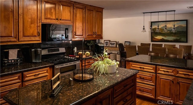 kitchen with dark stone counters, stainless steel range with gas stovetop, black microwave, visible vents, and backsplash