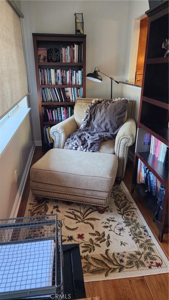 sitting room with baseboards and wood finished floors