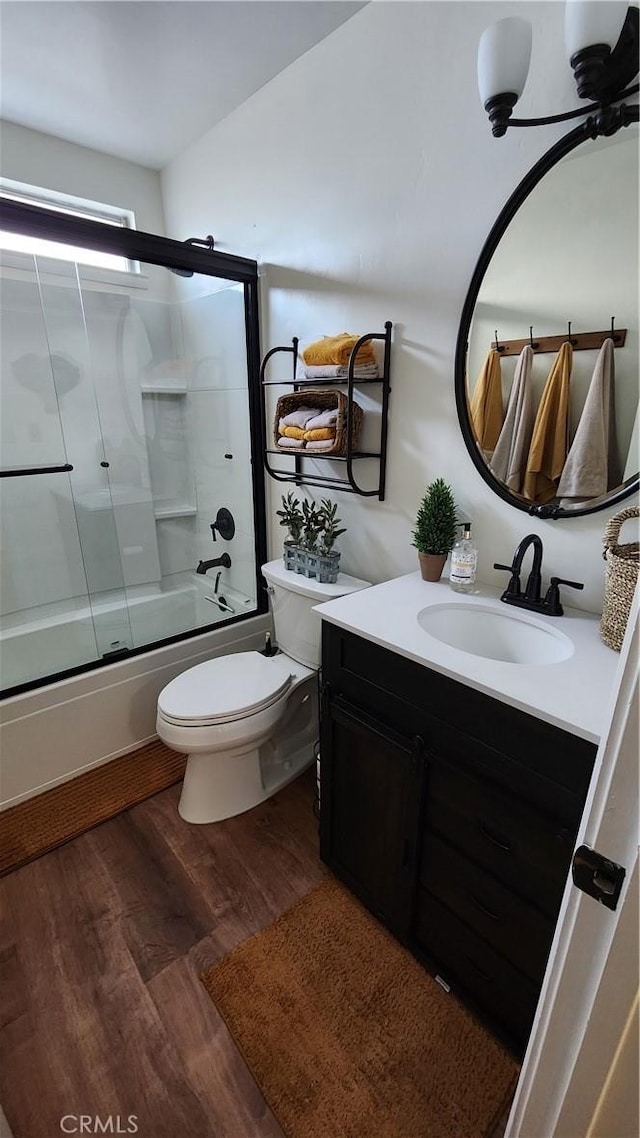 bathroom featuring shower / bath combination with glass door, vanity, toilet, and wood finished floors
